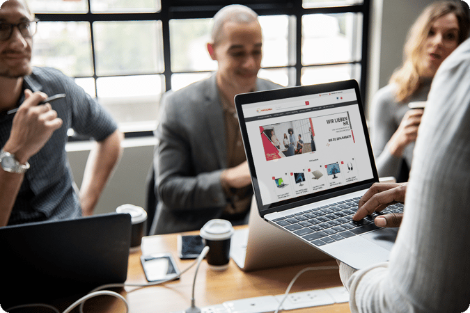 Viele Personen sitzen an einem Tisch mit der Vorteilswelt offen auf dem Laptop